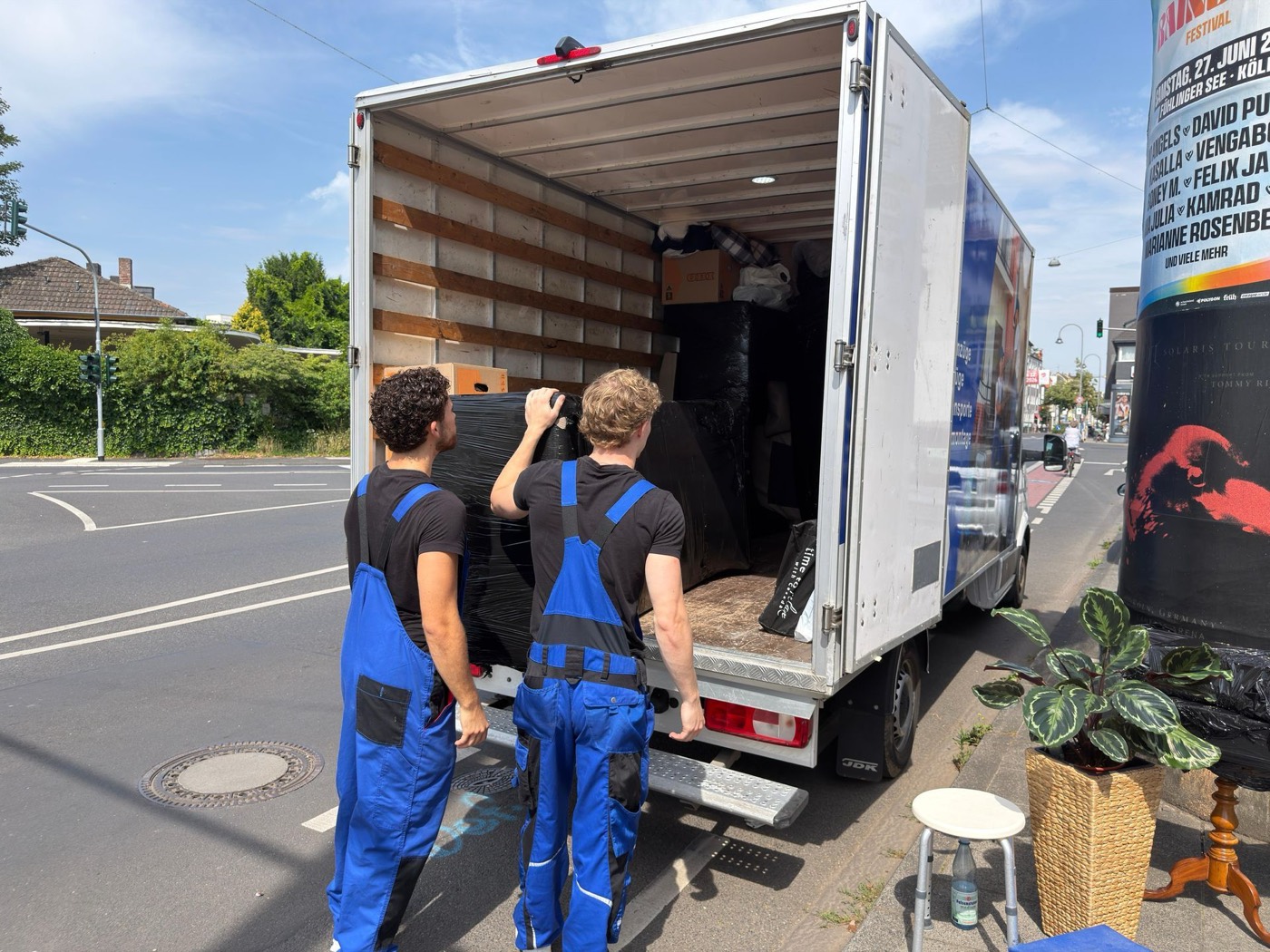 Zwei Umzugshelfer laden ein Sofa in den Wagen